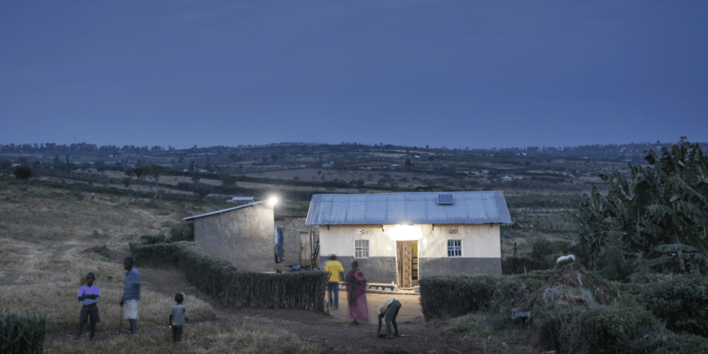 Solar lit house at dusk in village with people